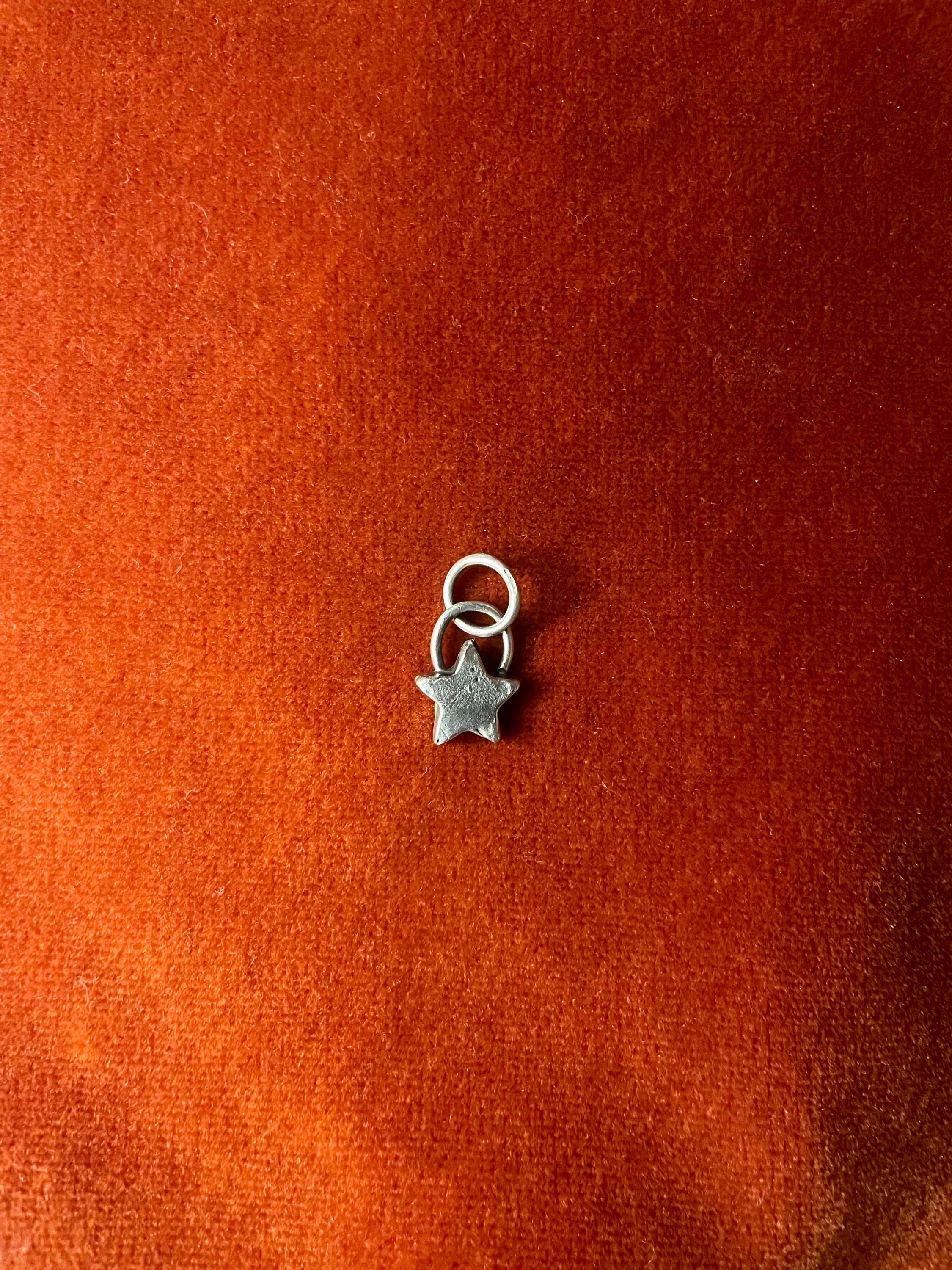Silver star charm on a textured orange background.