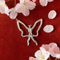 Butterfly-shaped silver pendant on a red background with cherry blossoms