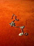 Silver floral vine charm on an orange velvet background.