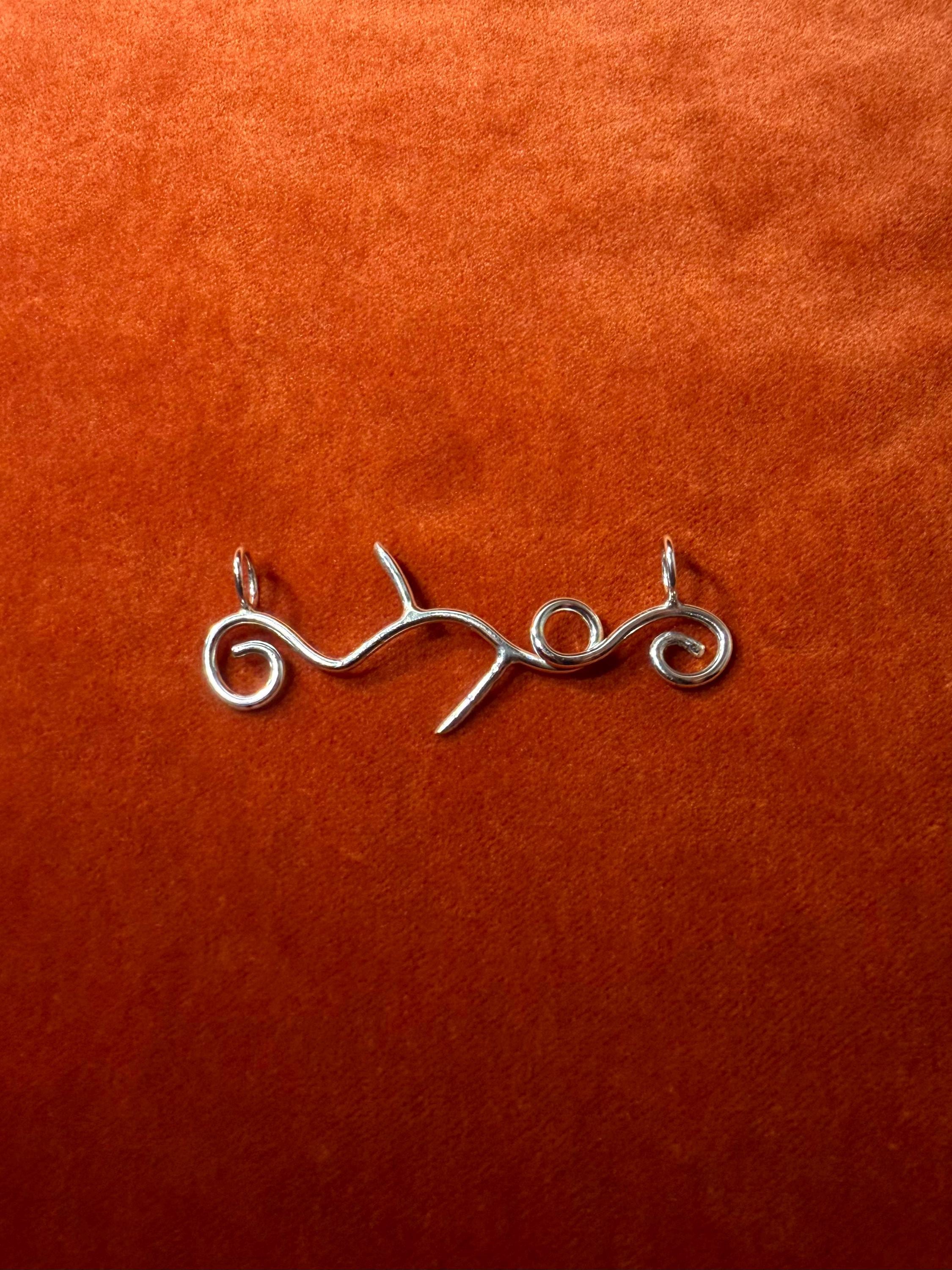 Silver vine pendant on a orange textured background.