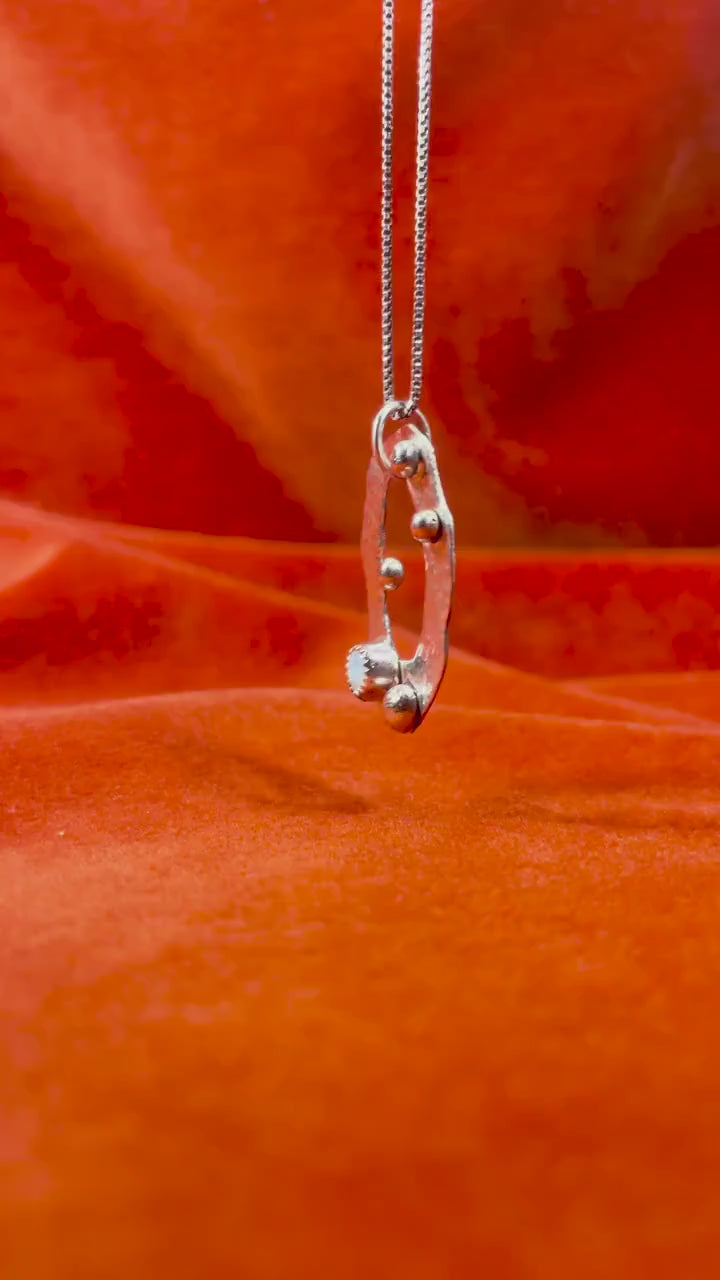 Silver celestial charm with an opal stone stone on a silver necklace.