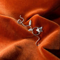 Silver jasmine flower vine charm laying against an orange velvet background.