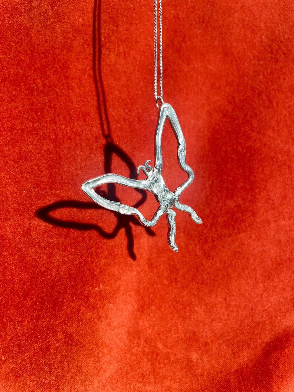 Silver butterfly pendant on a red background