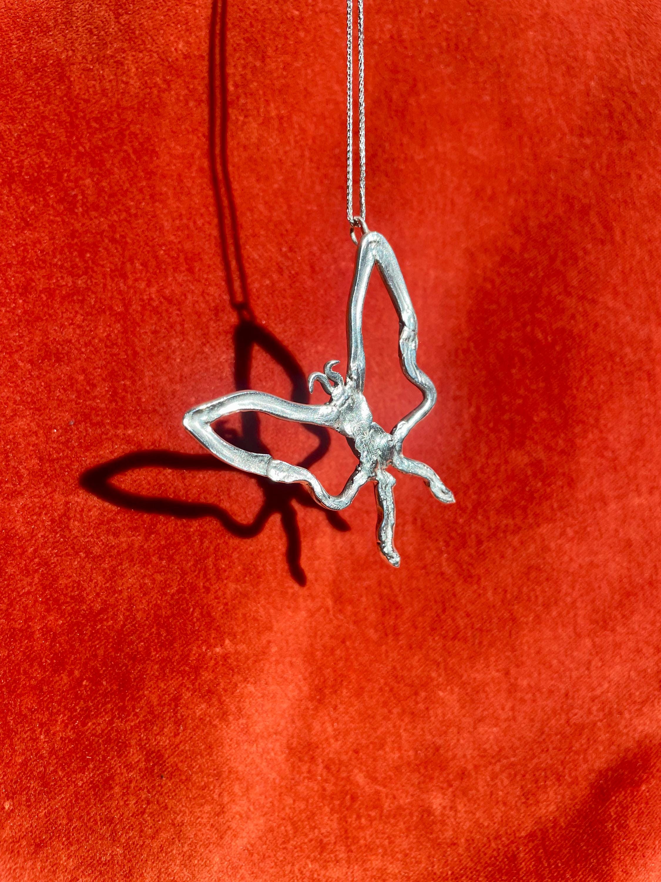 Silver butterfly pendant on a red background