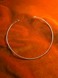 Silver wire hook choker with hook clasp. Choker is opened an and stage on a orange velvet background.