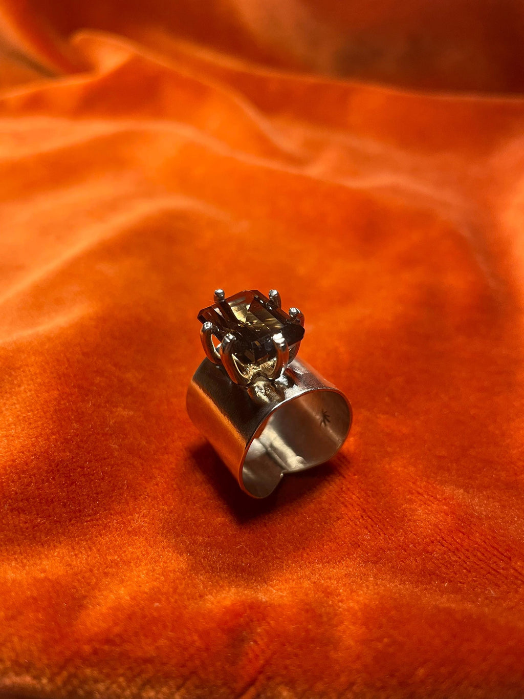 Silver ring with a smoky quartz emerald cut stone, set within five prongs on top of the large band. 